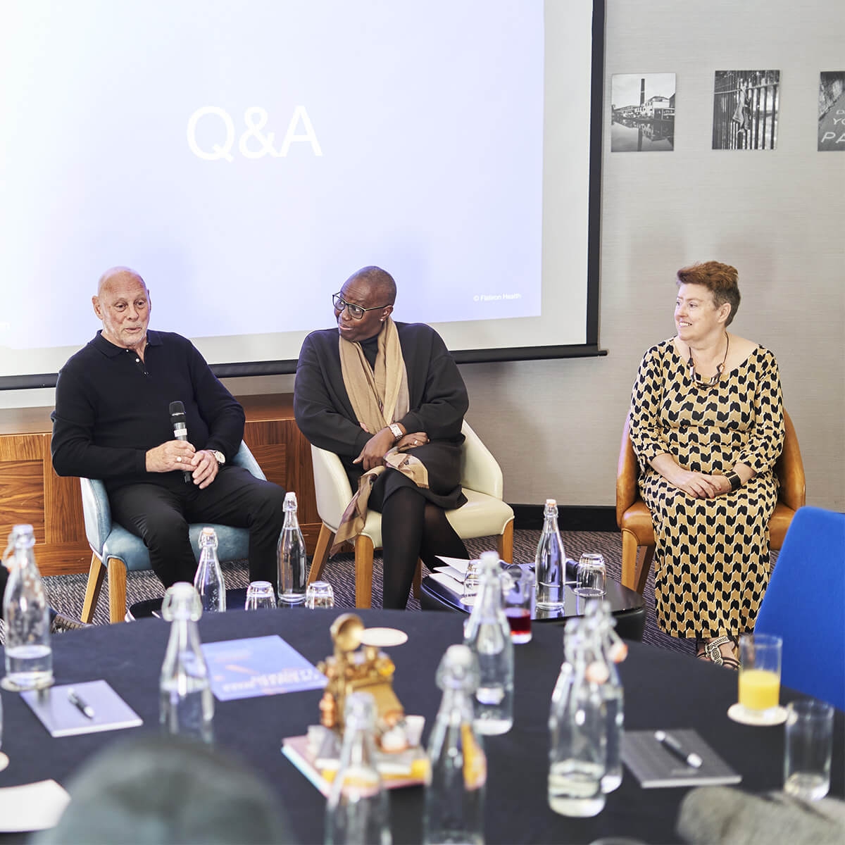 three members of the patient voices panel sitting in chairs in front of a presentation screen